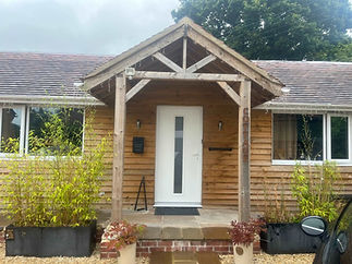 A cosy wooden cottage entrance with a white door and a "COTTAGE" sign