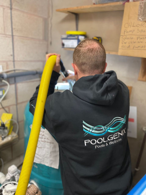 A professional wearing a Poolgenix uniform and holding a pipe.