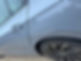 Silver car with visible scratches on the rear door near the wheel, parked on a gravel road