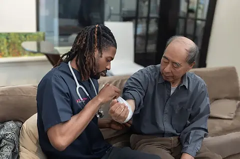 Healthcare professional bandaging an elderly man's arm