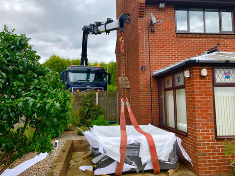 A crane lifting a large bed out of a house