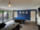 Garage converted into a stylish game room featuring a blue pool table, bar area, and large windows