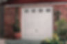 A white garage door with windows, surrounded by a brick wall