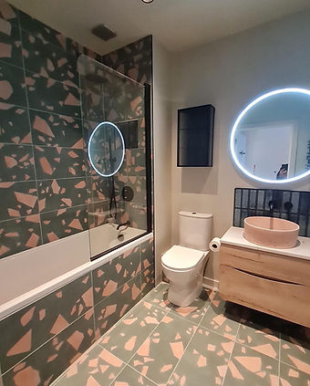 A stylish bathroom featuring bold patterned wallpaper, a round backlit mirror, and a sleek vanity setup