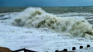 A large wave crashes onto a shore