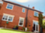 A charming red brick house with a lush green lawn