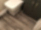 A bathroom corner featuring a white toilet and vinyl flooring