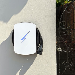 Electric vehicle charging station with a blue lightning bolt symbol mounted on a white wall