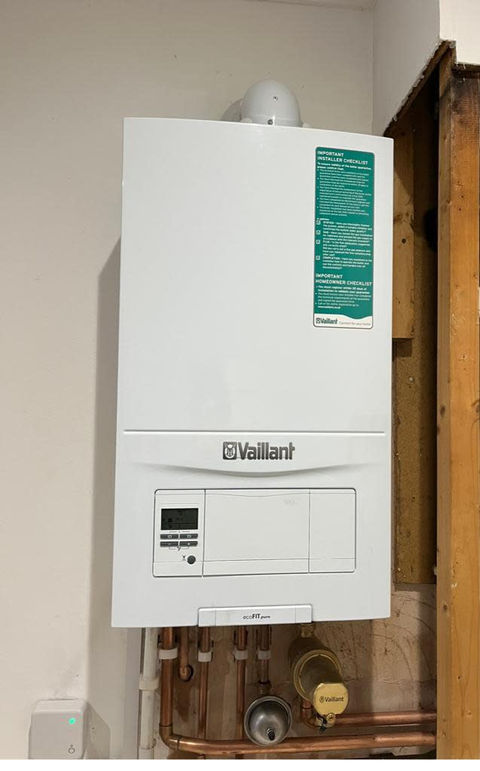 A gas boiler mounted on a wall with visible pipes