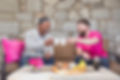 Two men are sitting on a couch, raising coffee cups in a toast to each other