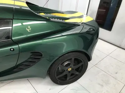 Close-up of a green sports car's rear side with black wheel and yellow stripe