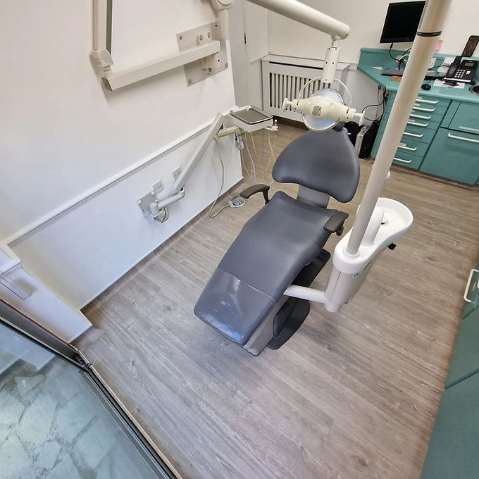 Dental office with a grey dentist chair centered, surrounded by equipment
