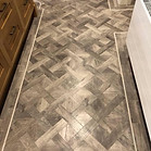 A close-up of a modern herringbone pattern wood-effect floor