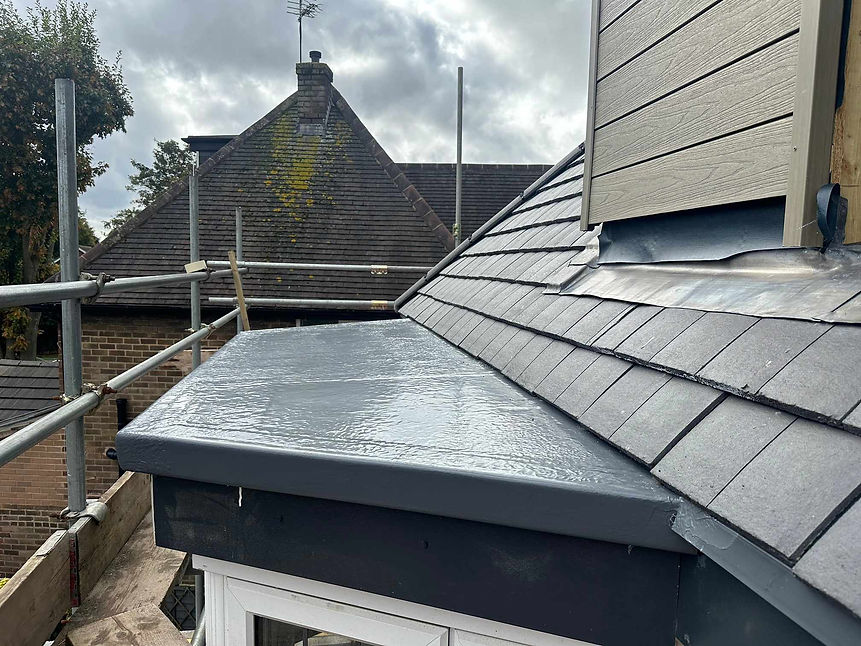 A rooftop view featuring a flat roof section, slate shingles, and scaffolding
