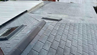 Flat and sloped grey slate roofs with two skylights