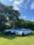 A white Hummer limo and a white Chrysler limo parked on green grass