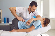 A chiropractor performing a lumbar adjustment to treat lower back pain