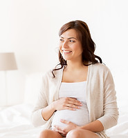 A smiling pregnant woman sitting during a childbirth hypnotherapy session