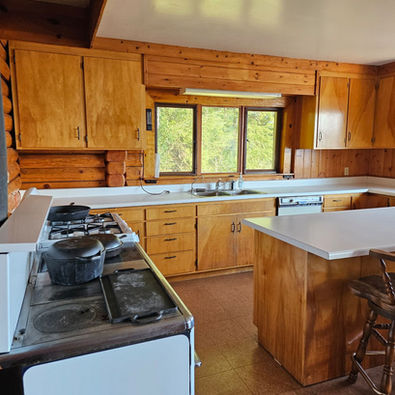 Wood interior, north facing view of Kitchen area, wood cook stove and propane stove, Waterfront Homestead for sale, Kupreanof Island Alaska