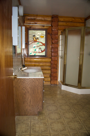 2nd floor, log interior, bathroom west facing window showing shower stall and sink, includes a toilet not seen in the image to the right.
