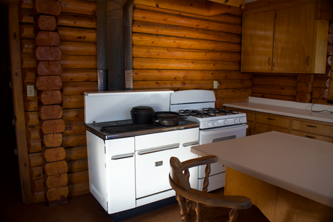 2nd floor - Kitchen wood cabinets, log interior, west facing view of Kitchen area, wood & propane cook stoves, Waterfront Homestead for sale, Kupreanof Island Alaska