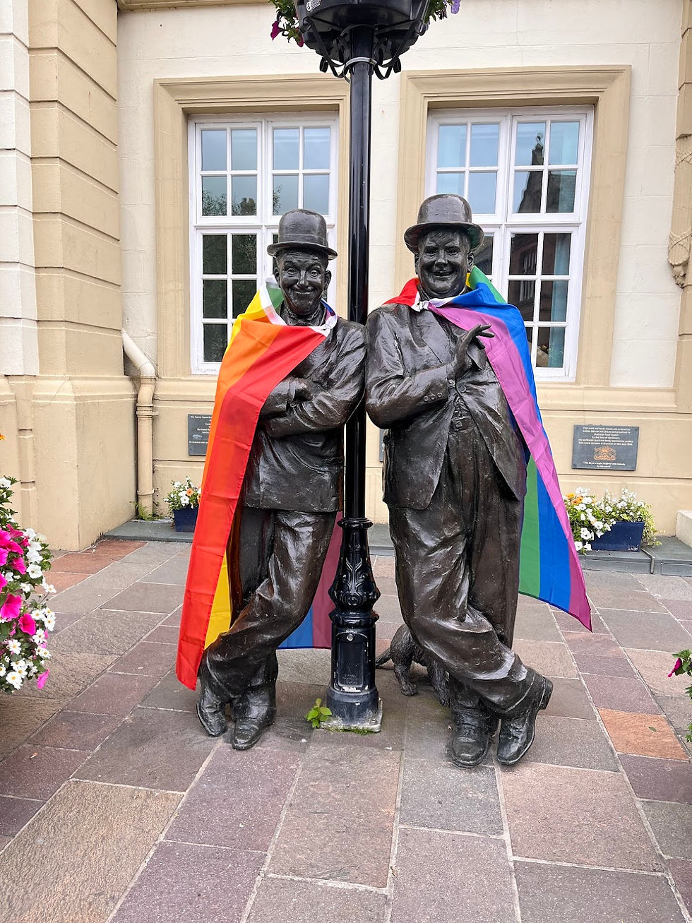 Ulverston's Laurel and Hardy statue in front of Coronation Hall, decorated in Pride flags