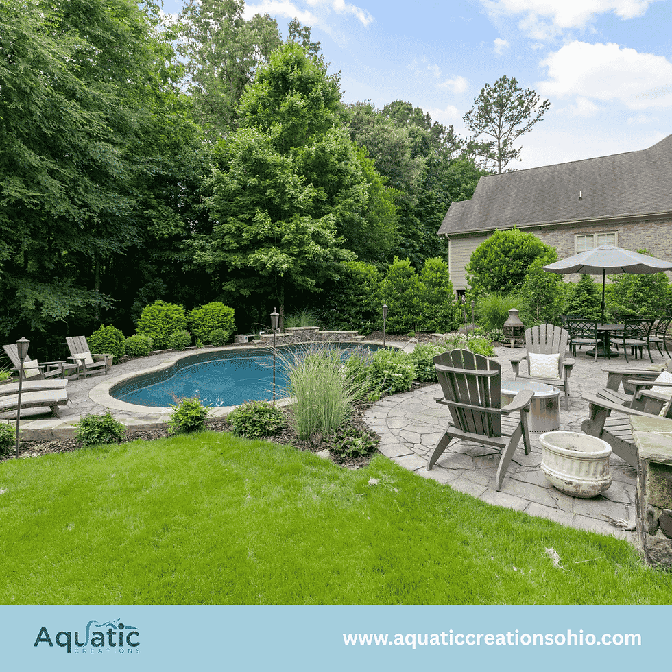Backyard pool patio with Adirondack chairs, umbrella, and lush trees beside a house; Aquatic Creations logo and website.