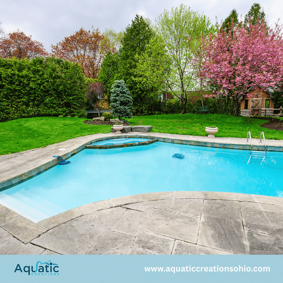 Blue backyard pool with stone patio, green lawn, pink blossoms, and banner text Aquatic Creations and aquaticcreationsohio.com