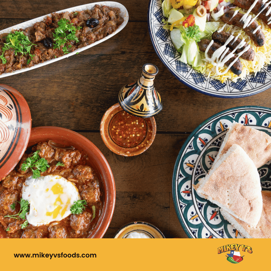 Moroccan dishes on patterned plates and bowls around a dipping sauce on a wooden table; www.mikeyvsfoods.com and Mikey V’s logo below.