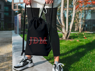 Person holding a black JDM Autoculture drawstring bag