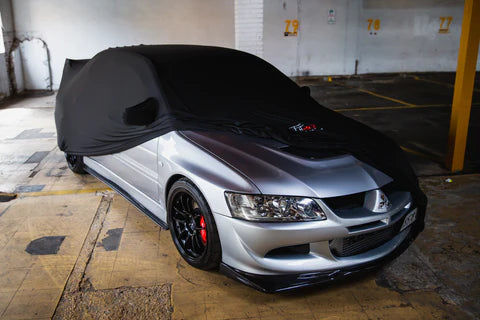 Silver Mitsubishi Lancer Evolution covered with a black car cover