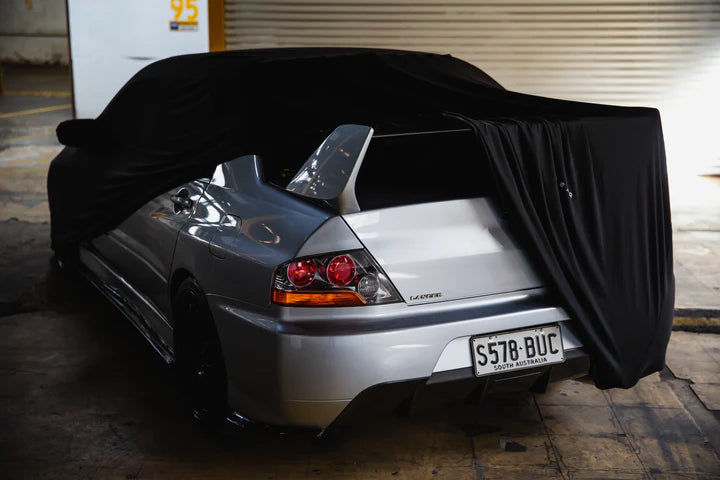 Silver Mitsubishi Lancer Evolution with a black car cover partially covering it, license plate S578-BUC