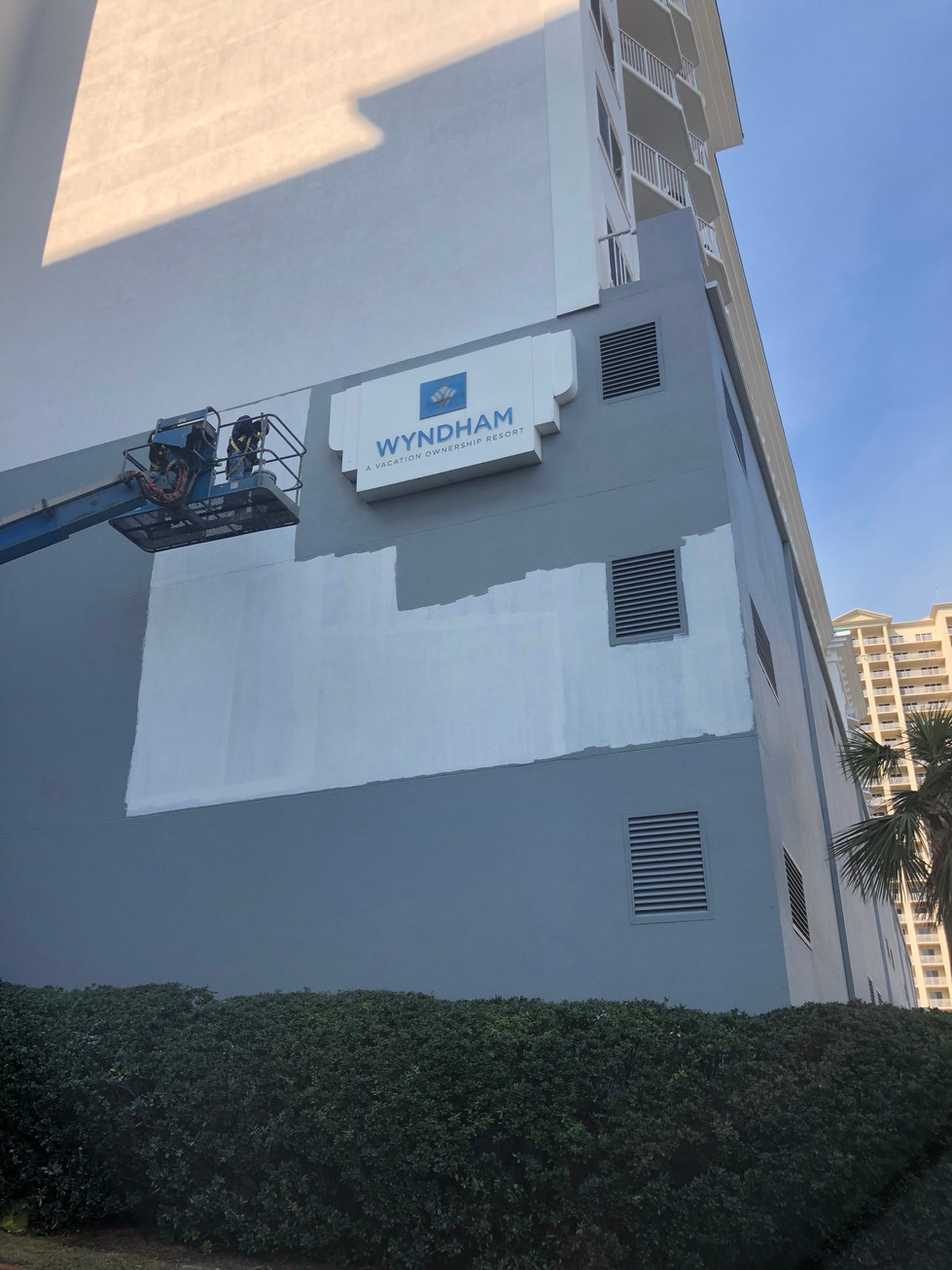 High-rise painting professionals applying protective coatings to a beachfront property.
