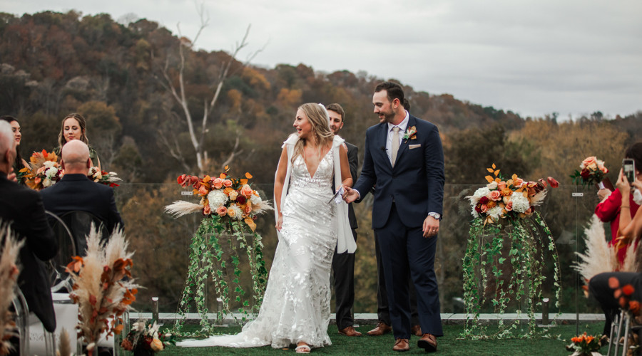 Bride and groom exiting ceremony with autumn flowers
