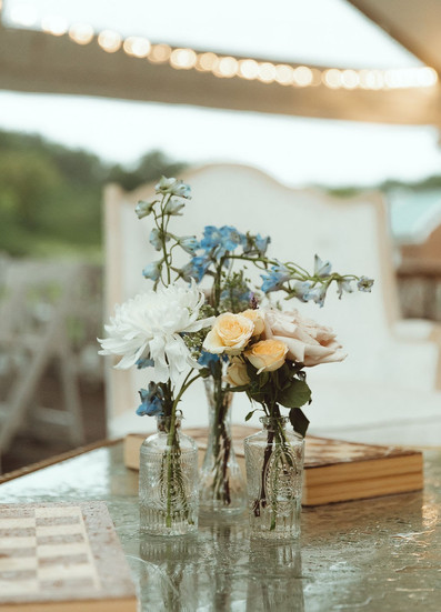 A trio of budvases with colorful blooms in a soft-seating area