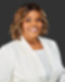 Smiling professional woman in a white blazer against a dark background.