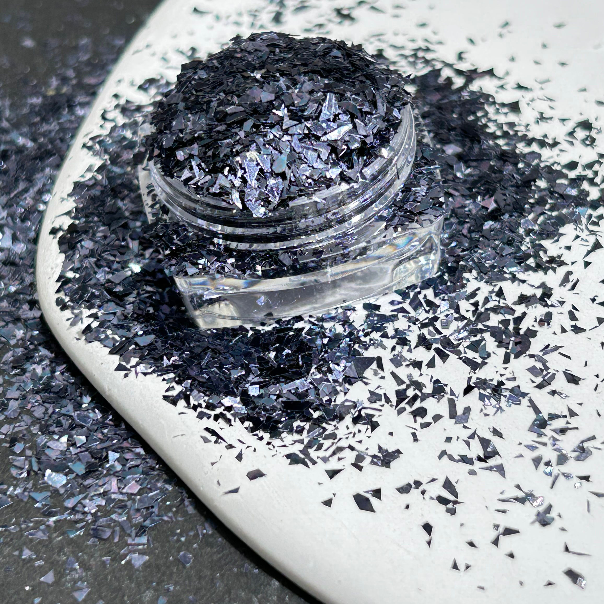 Zwarte flakes in potje Diamant Mica Poeder Silver op wit bordje epoxy-giethars.nl