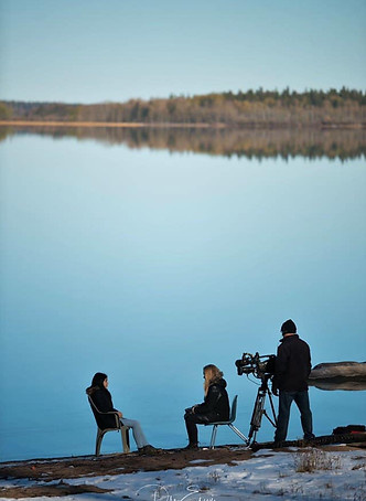 Pinehouse Lake Saskatchewan Photography member: Skyler Lariviere sitting in front of Pinehouse Lake being interviews by reports from CBC Saskatchewan for the documentary called: New Lens on Life"