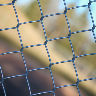 Close-up of a blue chain-link fence with a blurred background. Therapeutic Photography project by Dre Erwin.