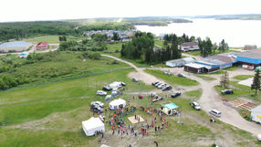 Aerial view of First Nations community in Sandy Bay during Canada Day, with people and colorful decorations.