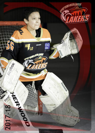 A young Pinehouse Lakers goalie stands proudly in Pinehouse Lake Arena, exuding enthusiasm and dedication during a photo opportunity.