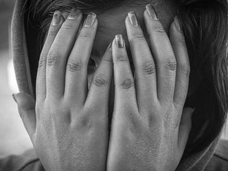 A young woman with her hands on her face, conveying deep emotions through a silent and expressive pose, representing the power of therapeutic photography.