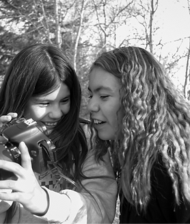 Two Pinehouse Lake youth looking at the back of a camera during some therapeutic photography
