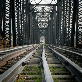 A black and white perspective shot looking down a long railway bridge. Part of Dre Erwin's youth photography program.