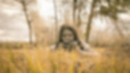 Girl lying in grass, taking and examining photos on a camera, engaging in therapeutic phot