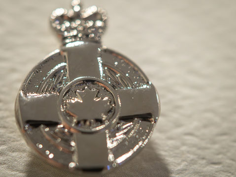 A detailed close-up shot of the silver Canadian Meritorious Service Medal featuring a crown and maple leaf design.