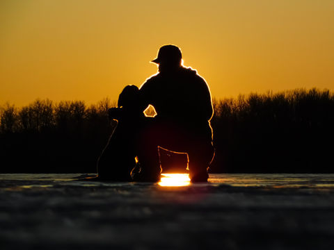 Dre Erwin and a dog silhouetted against a stunning sunset, inspiring youth through photography.