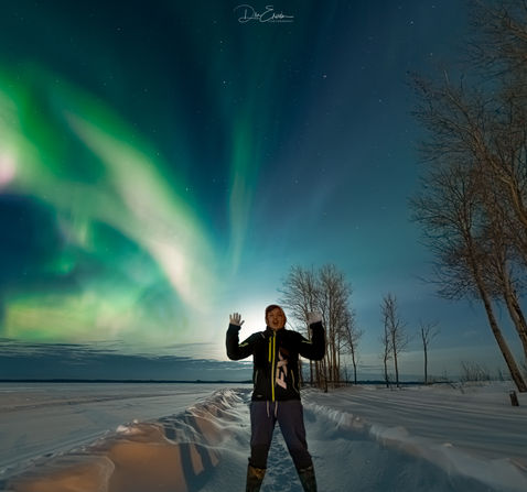 Man in front of the northern lights, in Pinehouse Lake