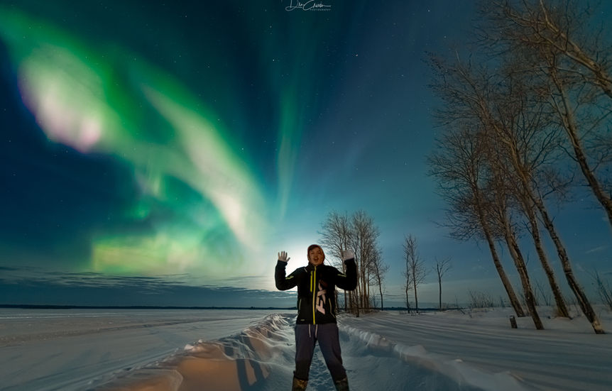 Man in front of the northern lights, in Pinehouse Lake