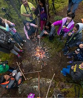 Group of youth members from Pinehouse Lake, sitting around campfire using photography to heal from trauma.